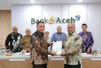 Direktur Utama Bank Aceh Fadhil Ilyas menerima Laporan Hasil Audit (LHA) opini Wajar Tanpa Pengecualian (WTP) atas laporan keuangan tahun buku 2025 dari perwakilan Kantor Akuntan Publik (KAP) Heliantono & Rekan di Gedung Action Center Bank Aceh, Banda Aceh, Jumat (13/1/2026). Foto: (Humas Bank Aceh)